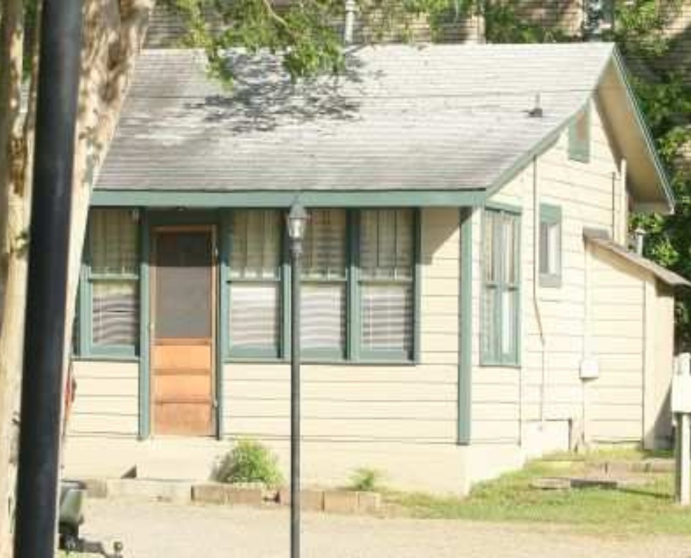 Exterior view of Cabin 7 surrounded by trees, featuring a spacious porch and large windows, ideal for family getaways.